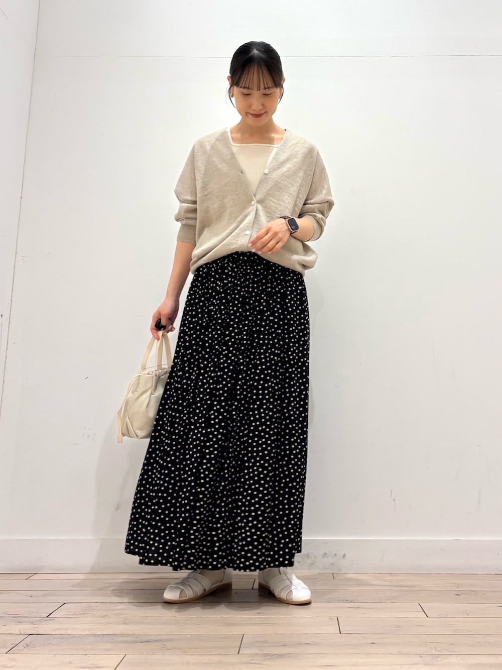 ブラック系のスカート、ホワイト系のショルダーバッグ、ホワイト系のサンダルを着用したレディースの春コーディネートの2枚目の写真