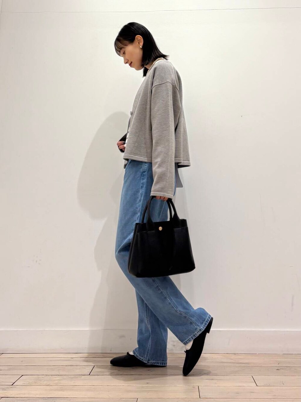 ブラック系のトートバッグ、グレー系のカーディガン/ボレロ、ホワイト系のノーカラージャケットを着用したレディースの冬コーディネートの5枚目の写真