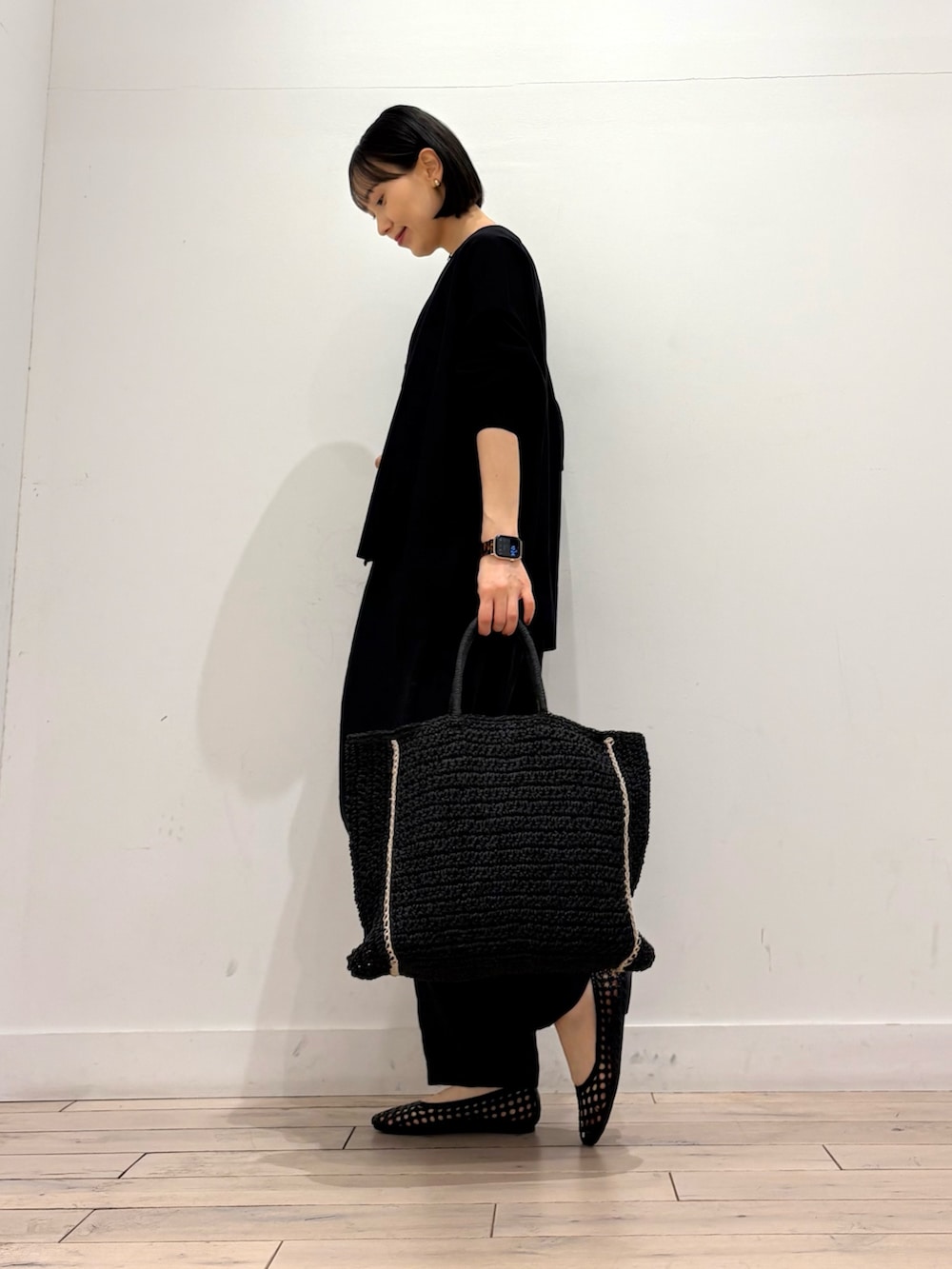 ホワイト系のタンクトップ、ブラック系のカーディガン/ボレロ、ブラック系のトートバッグを着用したレディースの春コーディネートの4枚目の写真
