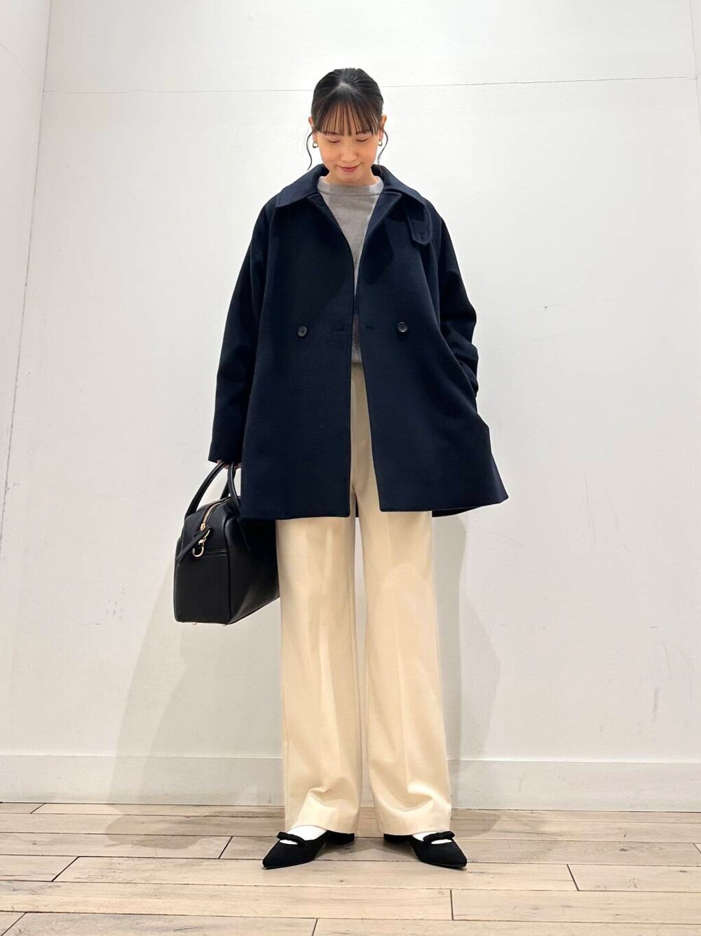ブラック系のボストンバッグ、ブラック系のパンプス、ブルー系のステンカラーコートを着用したレディースの冬コーディネートの4枚目の写真