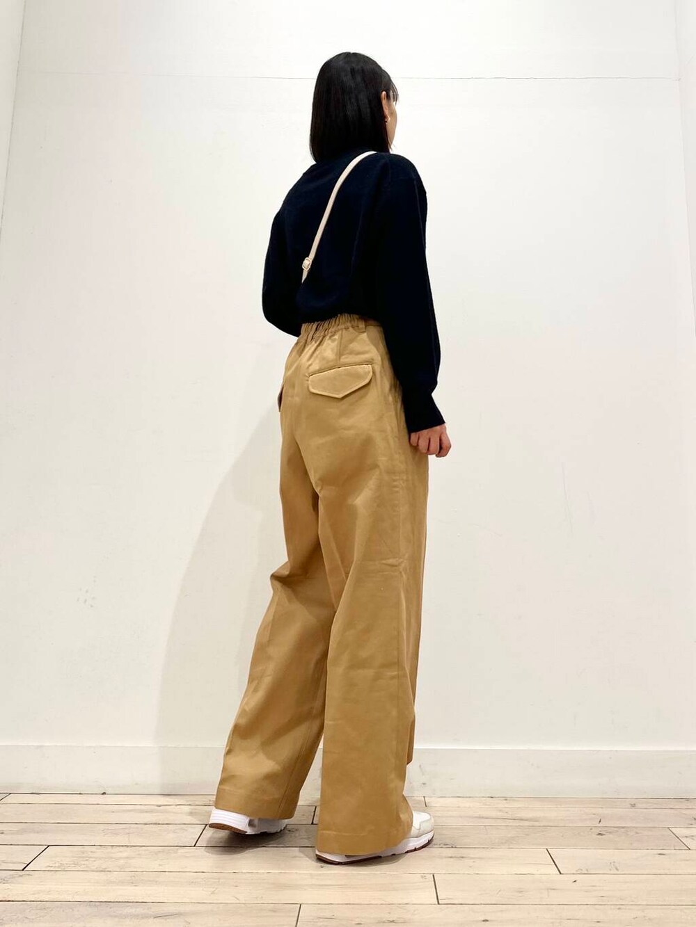 ベージュ系のチノパンツ、ホワイト系のスニーカー、ホワイト系のショルダーバッグを着用したレディースの秋コーディネートの3枚目の写真