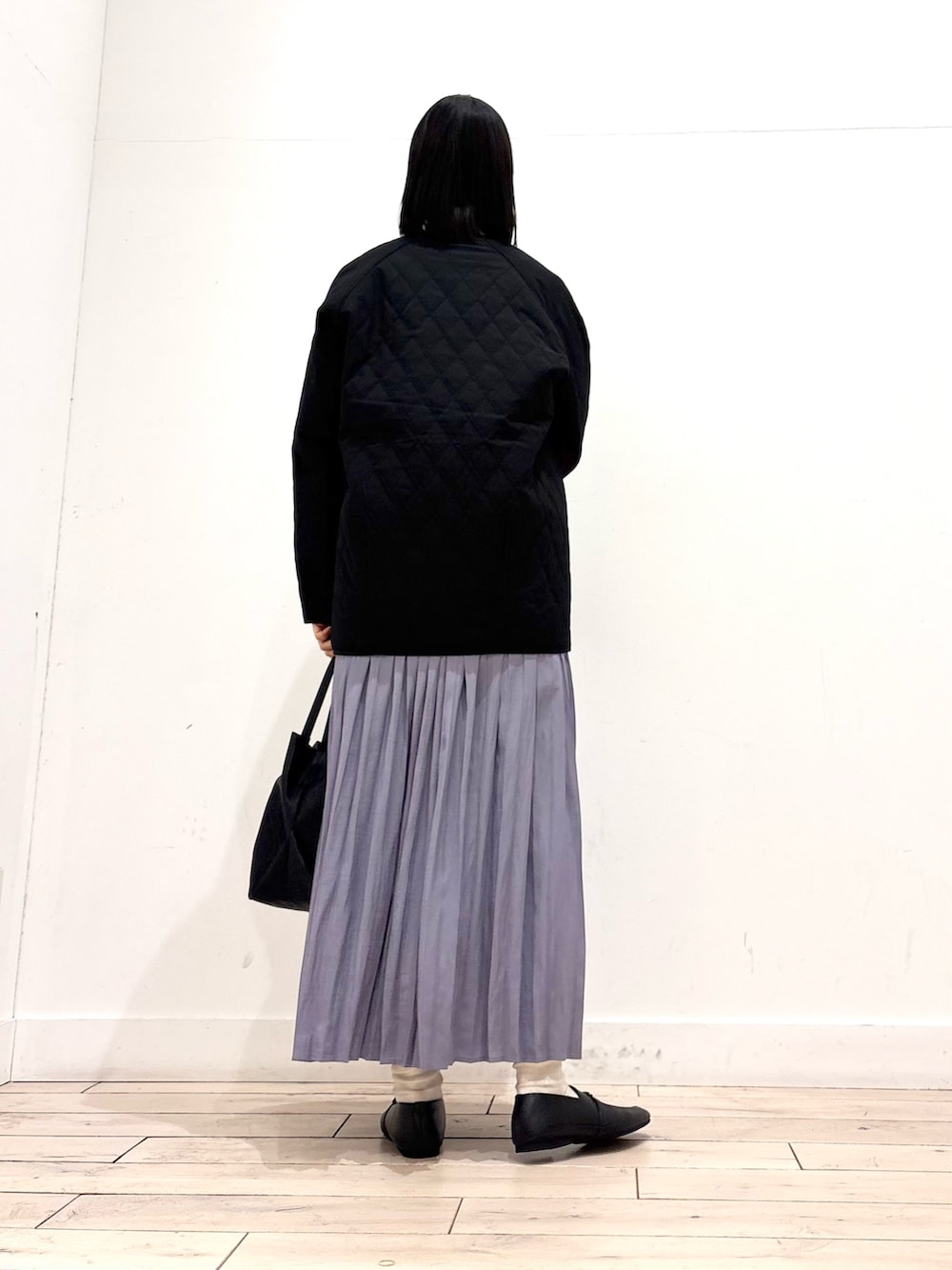 ブラック系のダウンジャケット/コート、グレー系のニット/セーター、パープル系のスカートを着用したレディースの春コーディネートの4枚目の写真