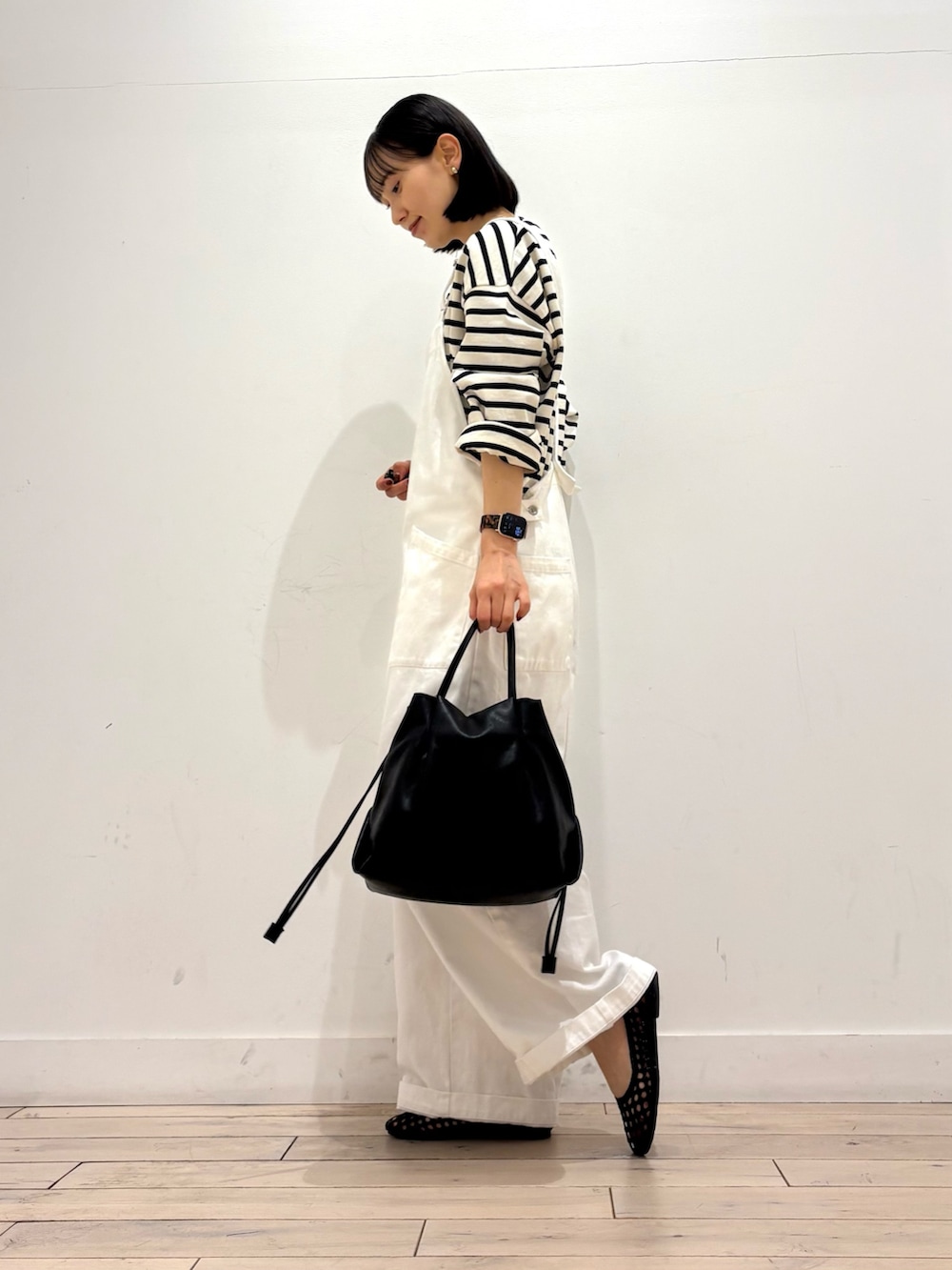 ホワイト系のTシャツ/カットソー、ホワイト系のサロペット/オーバーオール、ブラック系のショルダーバッグを着用したレディースの春コーディネートの2枚目の写真