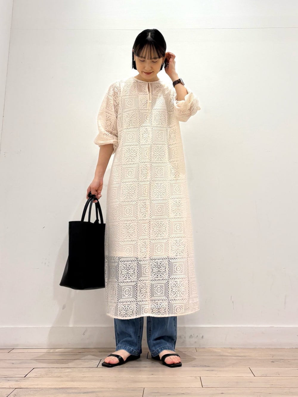 ベージュ系のワンピース、ブルー系のデニムパンツ、ブラック系のトートバッグを着用したレディースの春コーディネートの3枚目の写真