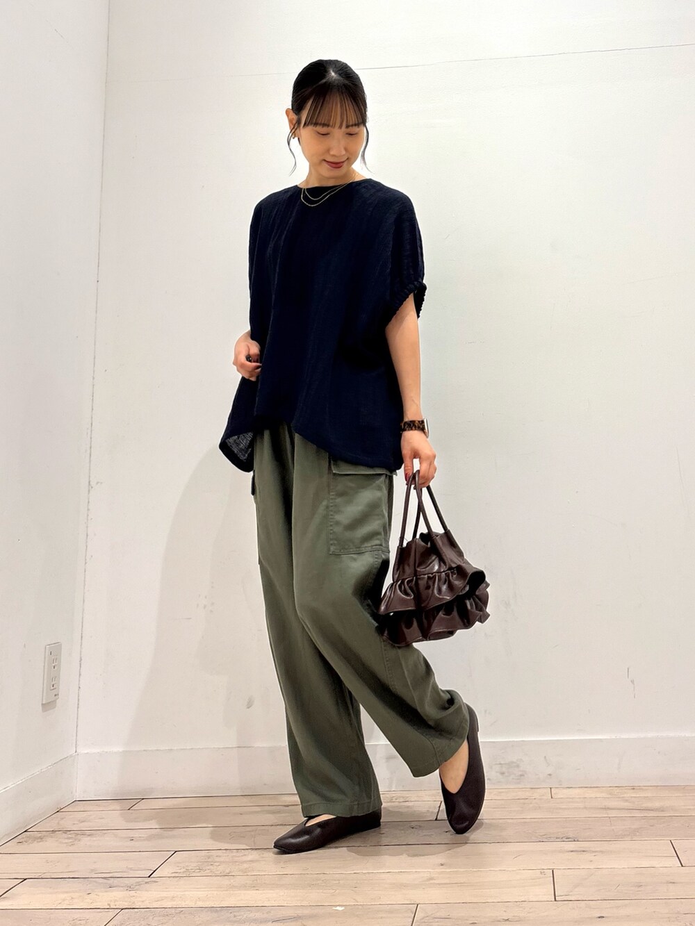 グリーン系のその他パンツ、ブラウン系のパンプス、ブラウン系のハンドバッグを着用したレディースの夏コーディネートの2枚目の写真