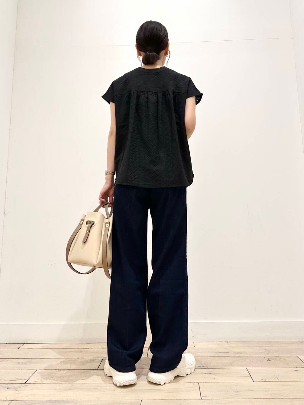 ホワイト系のトートバッグ、ホワイト系のスニーカー、ブラック系のシャツ/ブラウスを着用したレディースの夏コーディネートの3枚目の写真