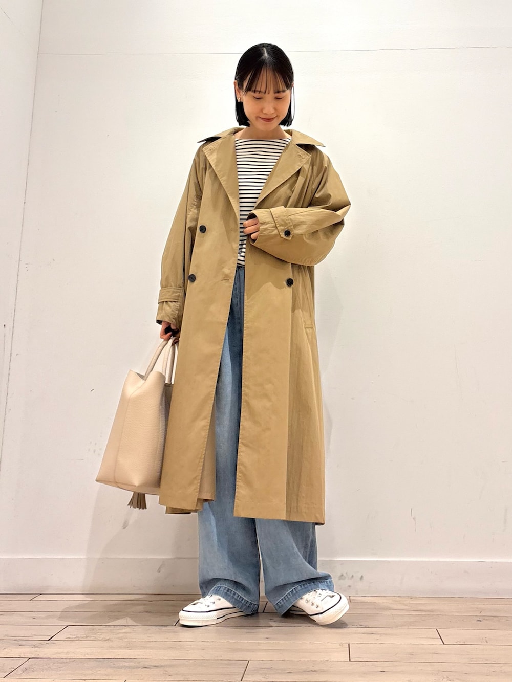 ホワイト系のTシャツ/カットソー、ブルー系のデニムパンツ、ベージュ系のトレンチコートを着用したレディースの春コーディネートの2枚目の写真