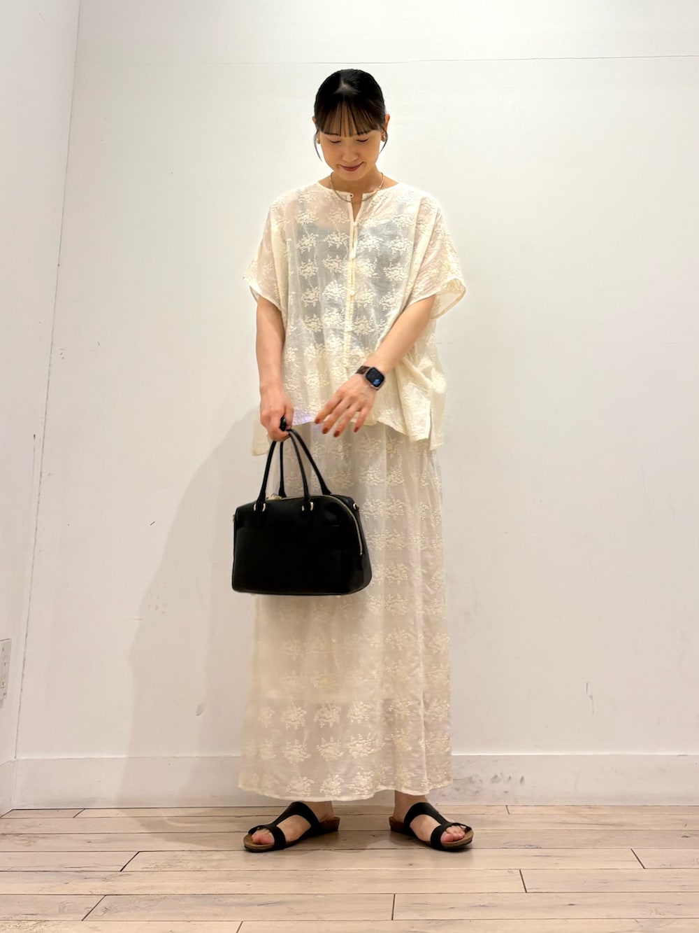 ホワイト系のシャツ/ブラウス、ホワイト系のスカート、ブラック系のサンダルを着用したレディースの夏コーディネートの2枚目の写真