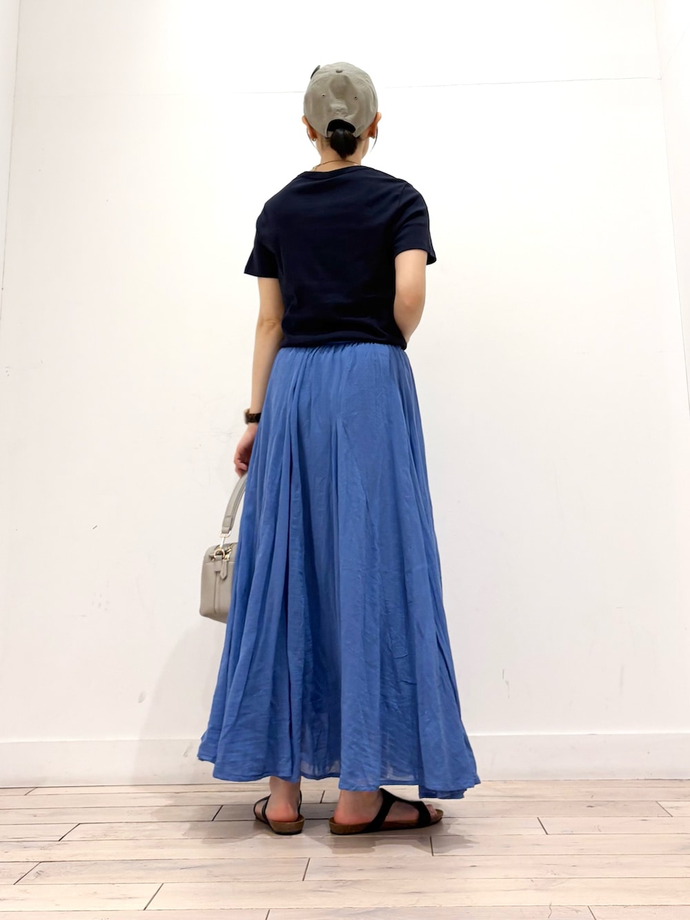 グレー系のショルダーバッグ、ブルー系のスカート、ブラック系のサンダルを着用したレディースの夏コーディネートの5枚目の写真