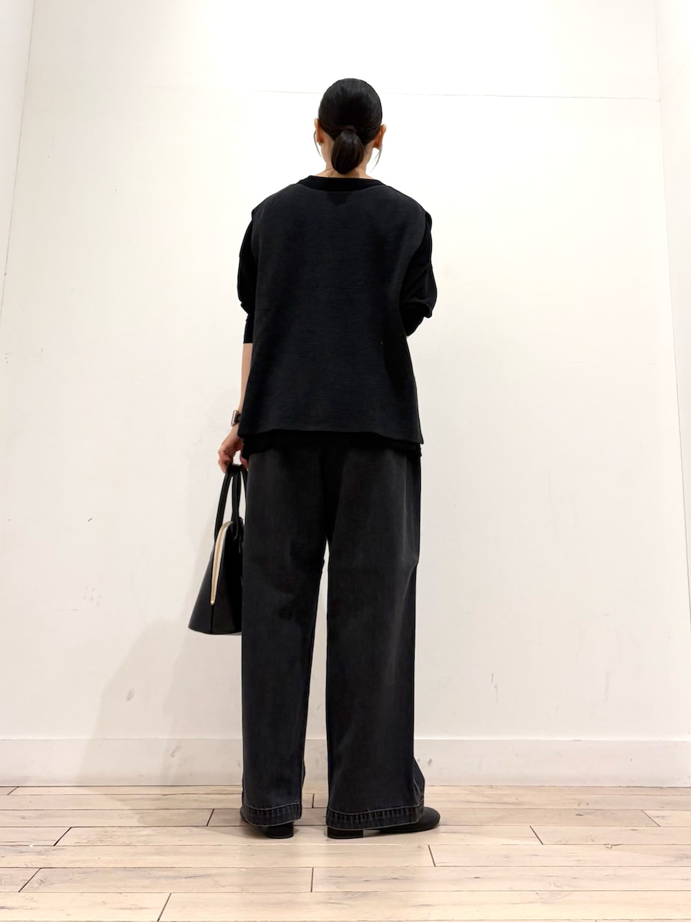 グレー系のベスト、ブラック系のTシャツ/カットソー、ブラック系のハンドバッグを着用したレディースの秋コーディネートの4枚目の写真
