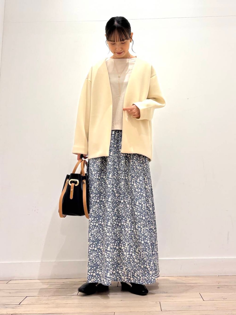 ブラック系のローファー、ブラック系のトートバッグ、ホワイト系のノーカラージャケットを着用したレディースの春コーディネートの2枚目の写真