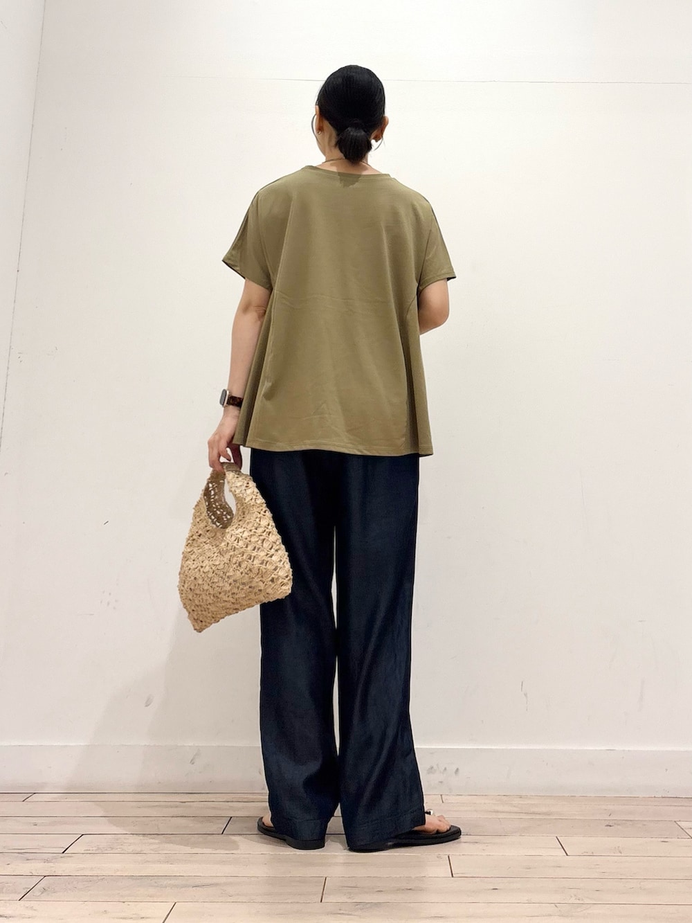 ブルー系のデニムパンツ、ベージュ系のハンドバッグ、ブラック系のサンダルを着用したレディースの夏コーディネートの4枚目の写真