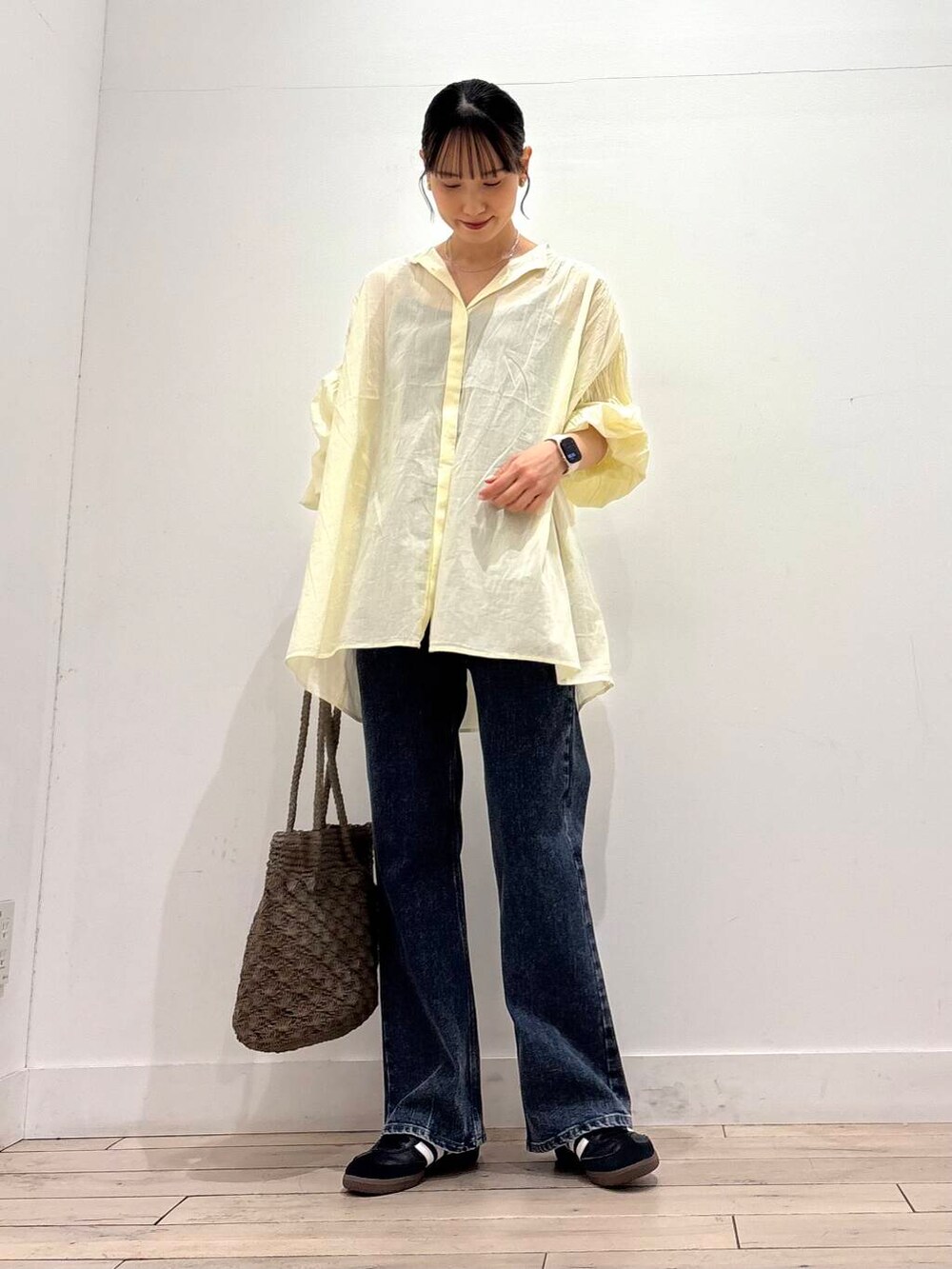 ブルー系のデニムパンツ、グレー系のトートバッグ、イエロー系のシャツ/ブラウスを着用したレディースの春コーディネートの2枚目の写真