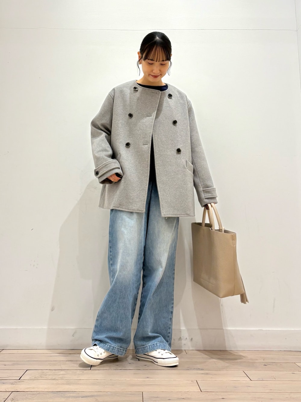 グレー系のピーコート、ブルー系のデニムパンツ、ホワイト系のトートバッグを着用したレディースの冬コーディネートの3枚目の写真