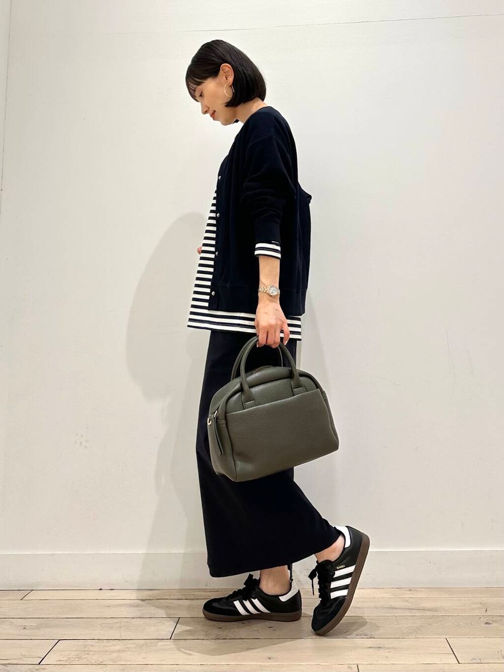 ブラック系のスニーカー、ブルー系のカーディガン/ボレロ、グリーン系のボストンバッグを着用したレディースの秋コーディネートの3枚目の写真