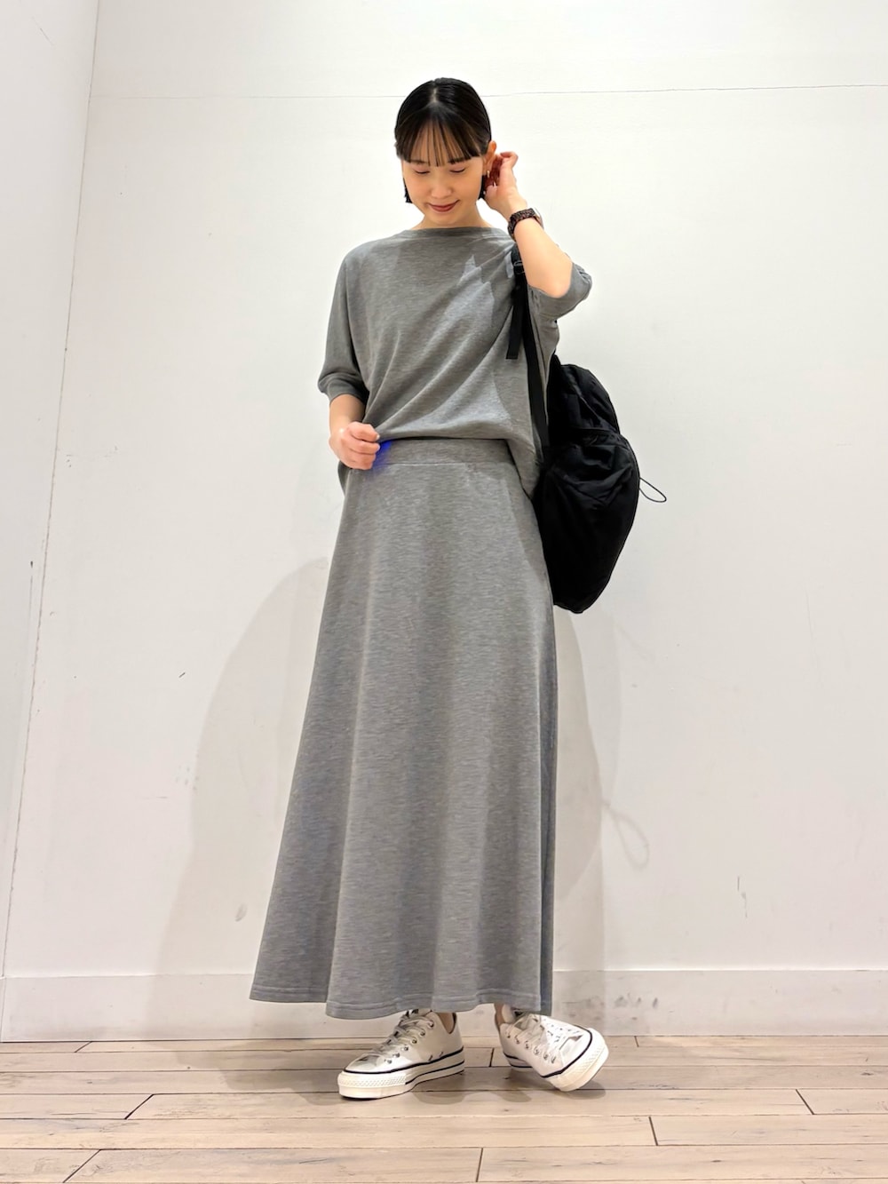 グレー系のTシャツ/カットソー、グレー系のスカート、ホワイト系のスニーカーを着用したレディースの春コーディネートの2枚目の写真