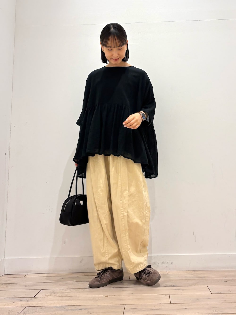 ブラック系のシャツ/ブラウス、ブラック系のボストンバッグ、イエロー系のその他パンツを着用したレディースの春コーディネートの2枚目の写真