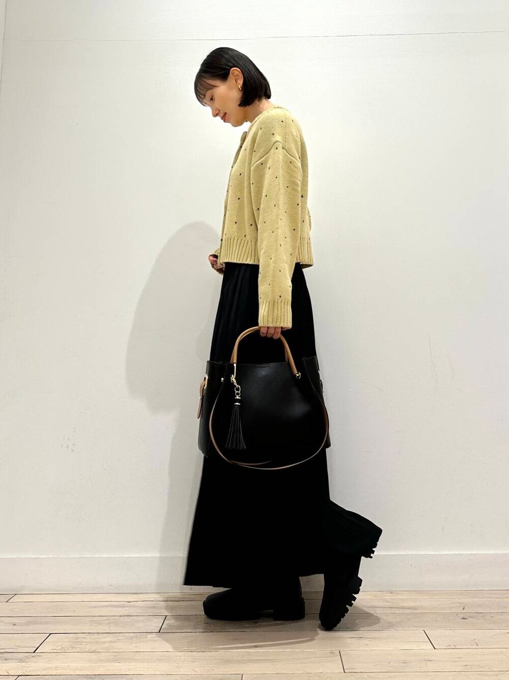ブラック系のトートバッグ、ブラック系のブーツ、ブラック系のスカートを着用したレディースの秋コーディネートの3枚目の写真