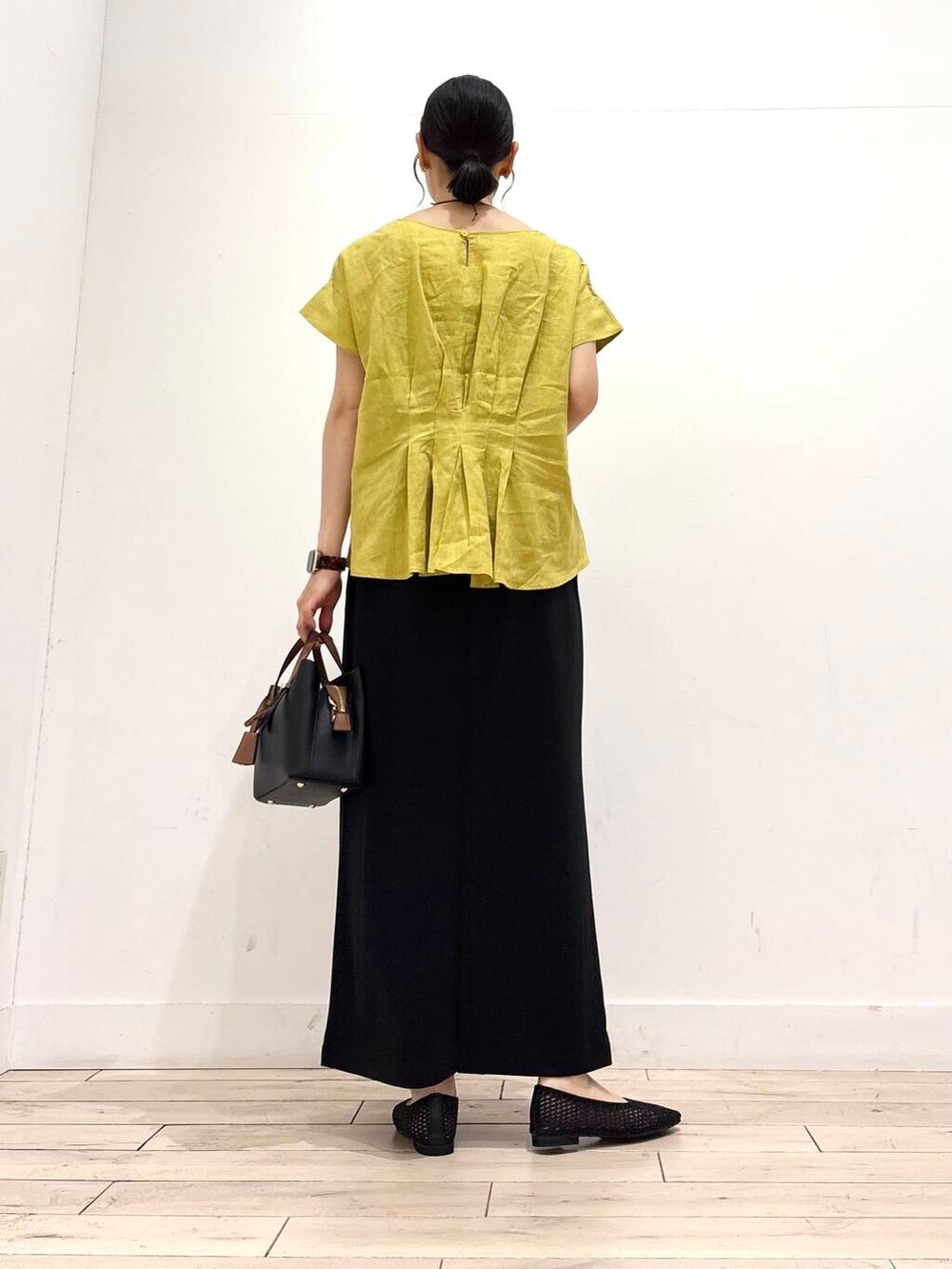 ブラック系のハンドバッグ、ブラック系のバレエシューズ、イエロー系のシャツ/ブラウスを着用したレディースの夏コーディネートの4枚目の写真
