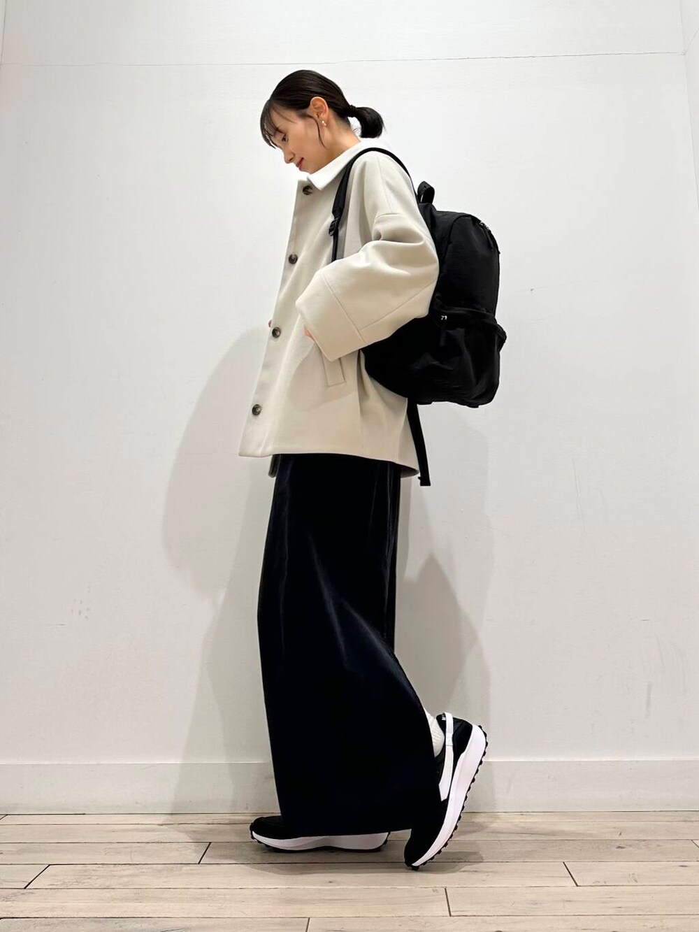 グレー系のその他アウター、グレー系のスカート、ブラック系のバックパック/リュックを着用したレディースの冬コーディネートの2枚目の写真