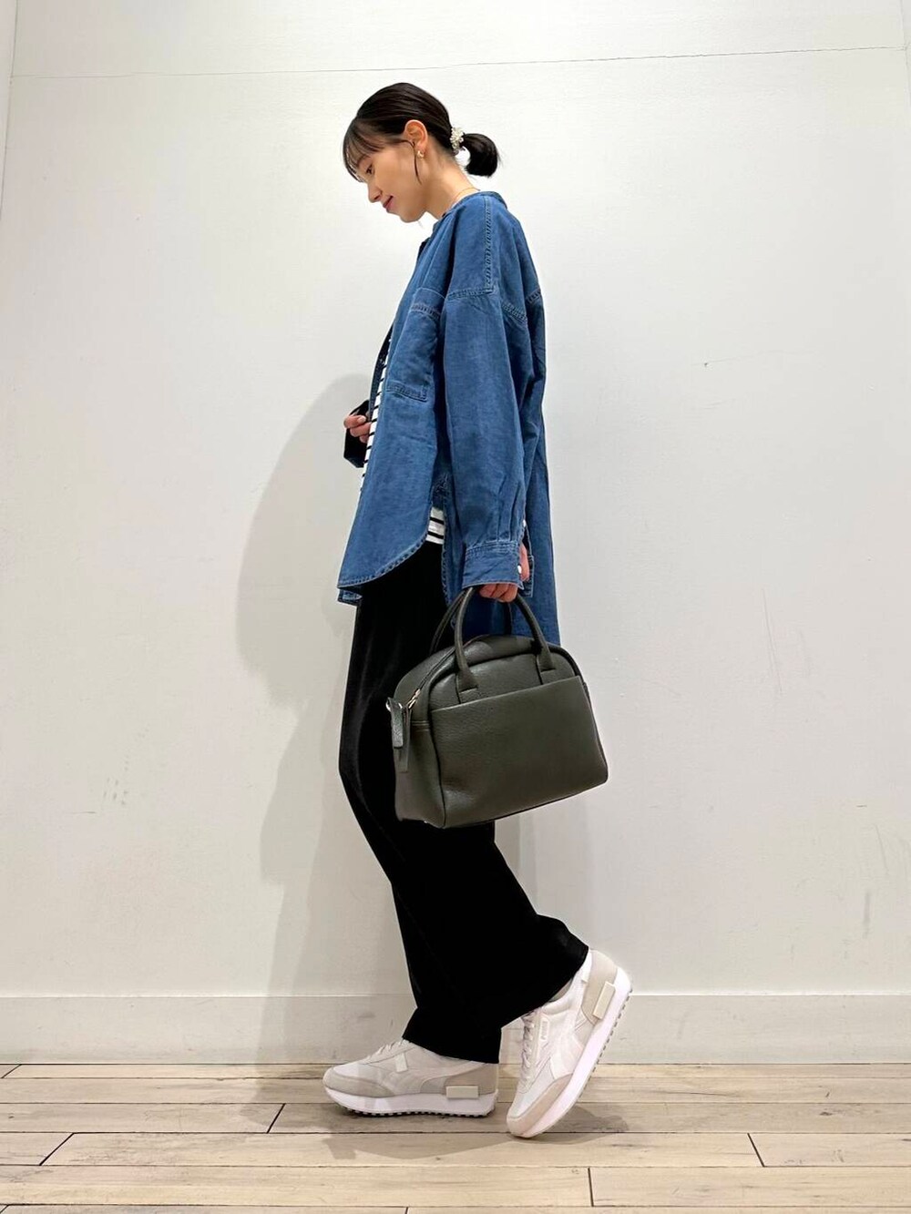 グリーン系のボストンバッグ、ブラック系のTシャツ/カットソー、ブルー系のシャツ/ブラウスを着用したレディースの冬コーディネートの2枚目の写真