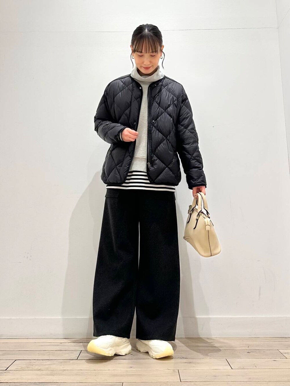 ホワイト系のスニーカー、ブラック系のダウンジャケット/コート、ホワイト系のボストンバッグを着用したレディースの冬コーディネートの4枚目の写真