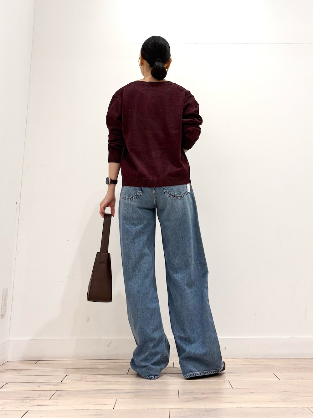 レッド系のカーディガン/ボレロ、ブルー系のデニムパンツ、ブラウン系のハンドバッグを着用したレディースの秋コーディネートの5枚目の写真