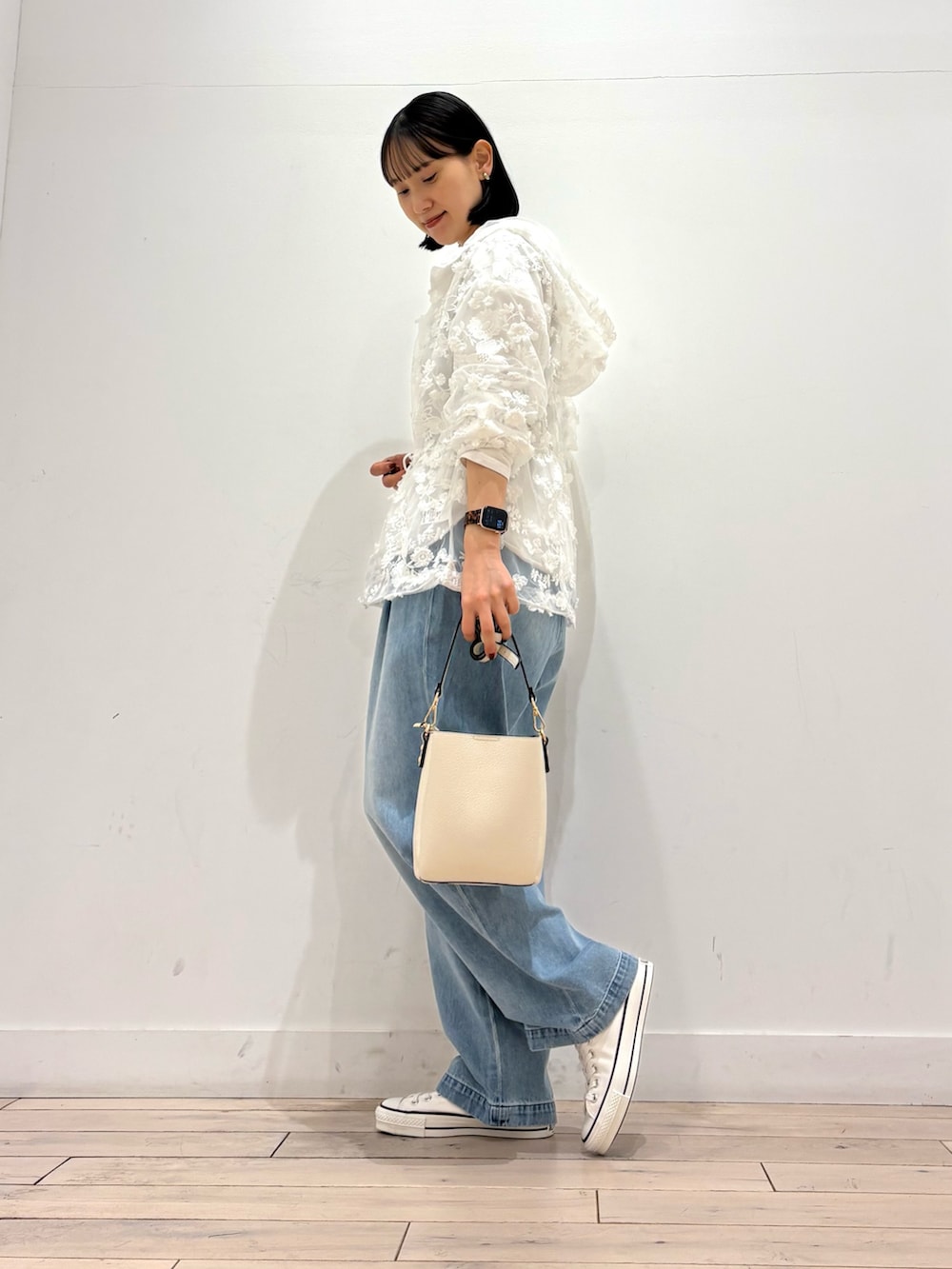 ホワイト系のショルダーバッグ、ホワイト系のスニーカー、ブルー系のデニムパンツを着用したレディースの春コーディネートの3枚目の写真