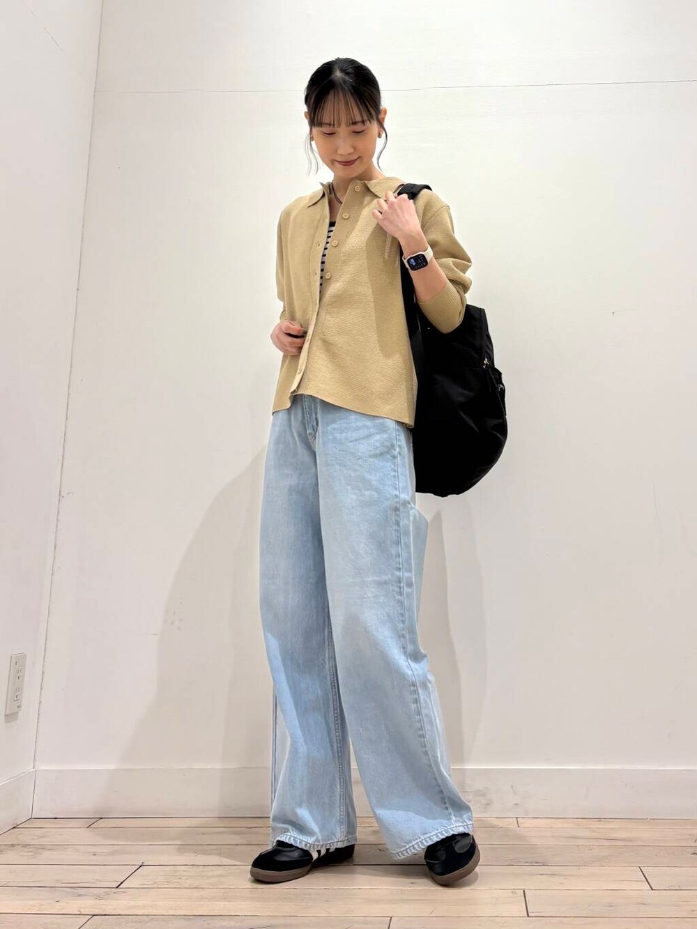 ホワイト系のタンクトップ、ブラック系のバックパック/リュック、ベージュ系のカーディガン/ボレロを着用したレディースの春コーディネートの2枚目の写真