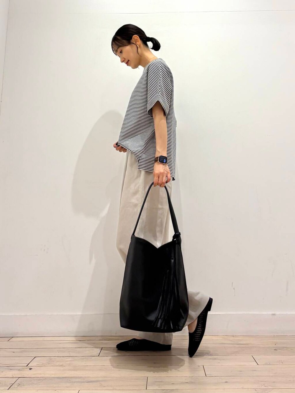 ブラック系のトートバッグ、ブラック系のバレエシューズ、ホワイト系のTシャツ/カットソーを着用したレディースの夏コーディネートの3枚目の写真