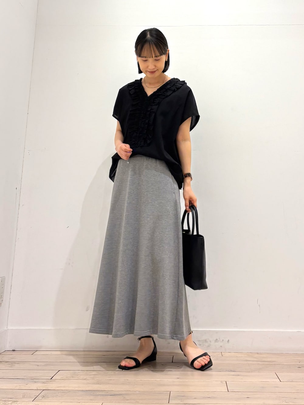 ブラック系のシャツ/ブラウス、グレー系のスカート、ブラック系のサンダルを着用したレディースの夏コーディネートの2枚目の写真