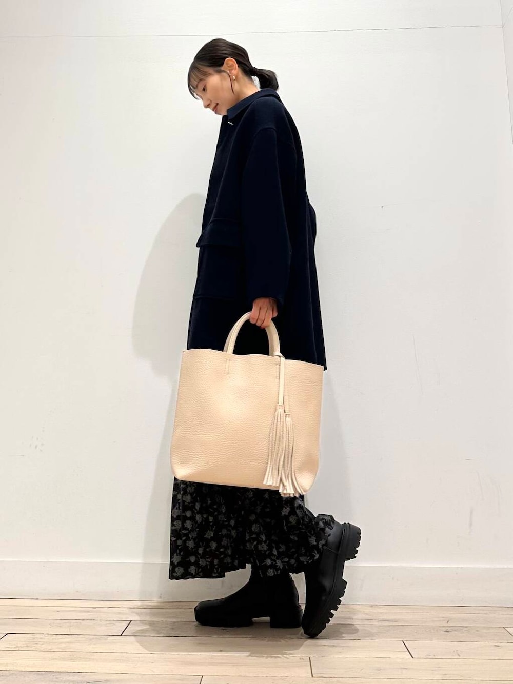 ホワイト系のトートバッグ、ブルー系のその他アウター、ブラック系のブーツを着用したレディースの冬コーディネートの2枚目の写真