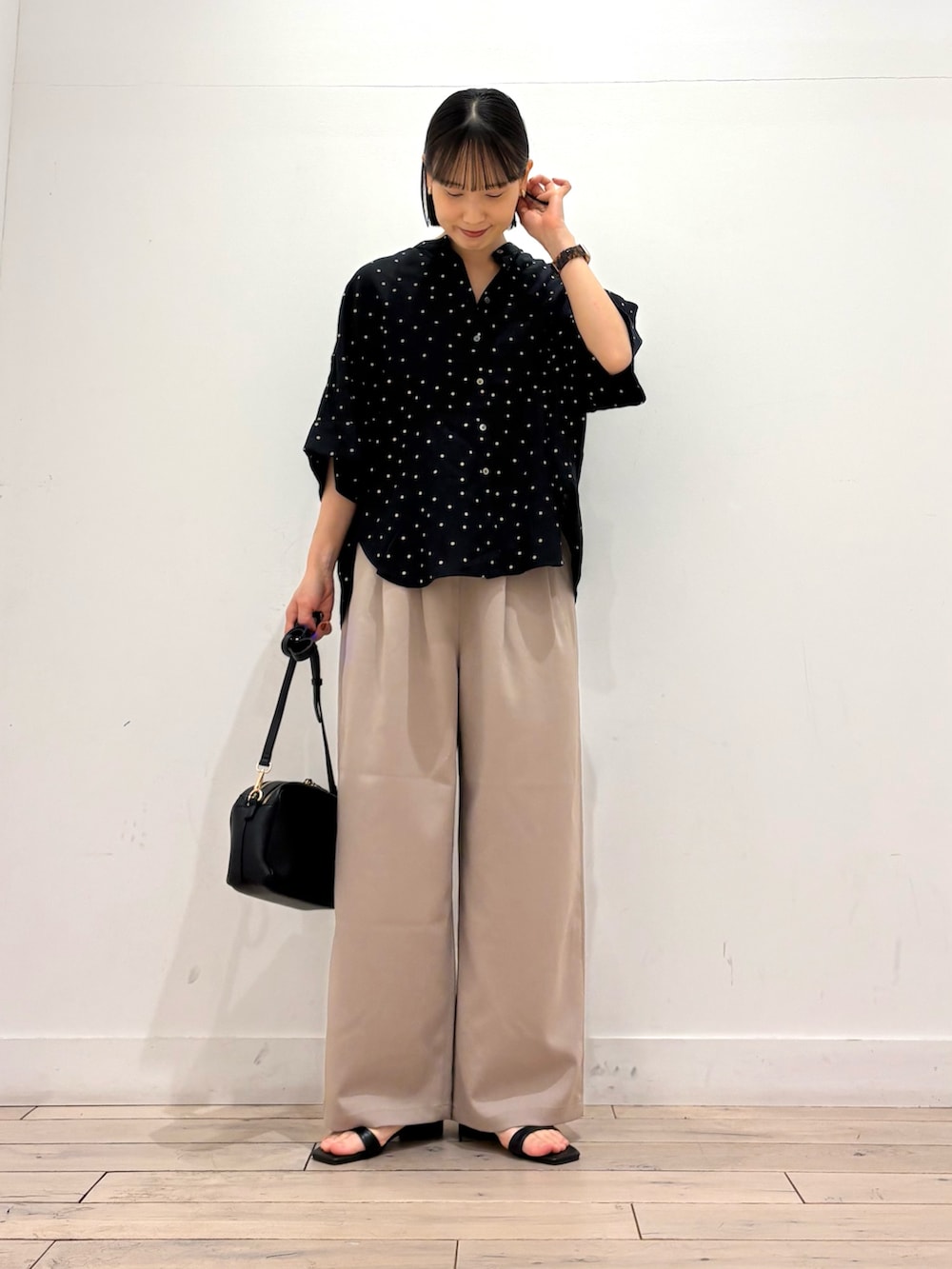ブラック系のシャツ/ブラウス、ベージュ系のその他パンツ、ブラック系のショルダーバッグを着用したレディースの春コーディネートの2枚目の写真