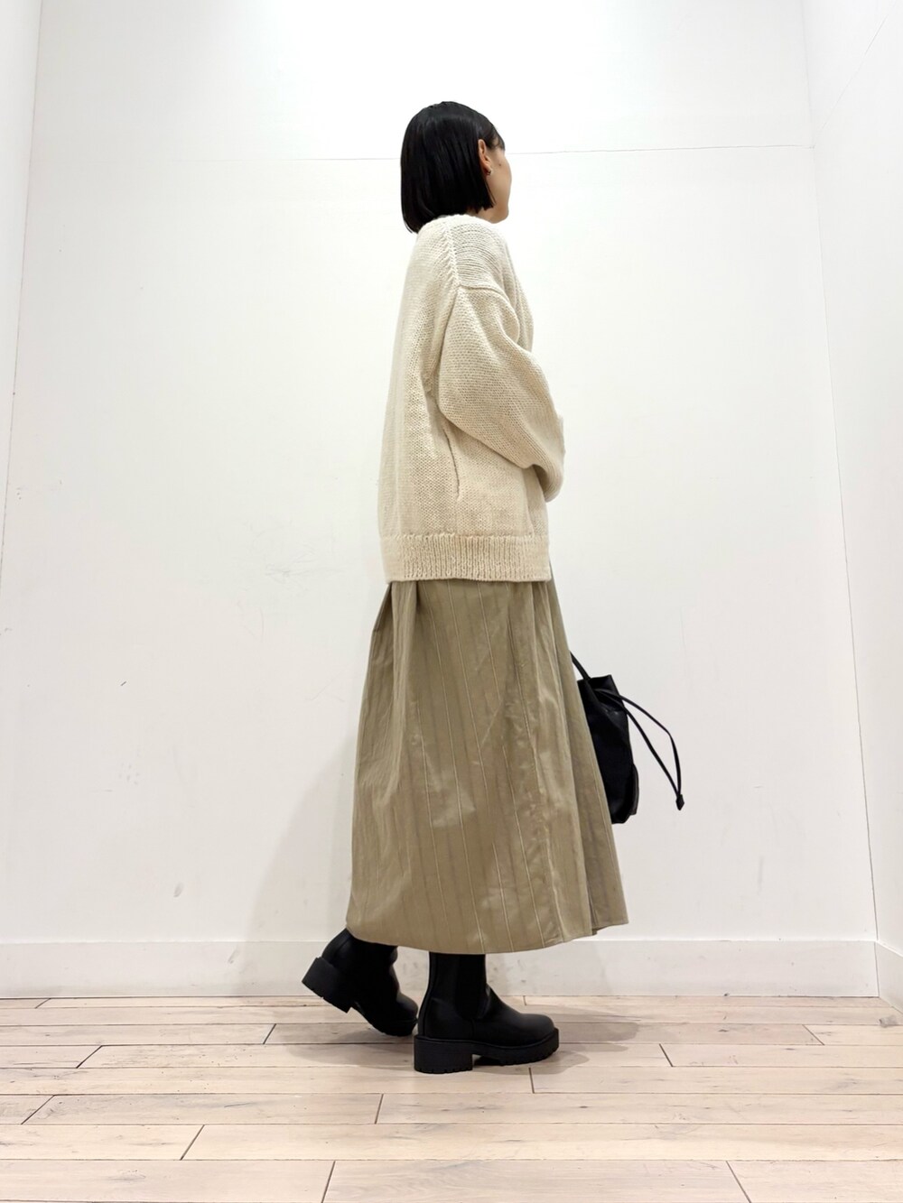 ホワイト系のニット/セーター、ブラック系のブーツ、ブラック系のショルダーバッグを着用したレディースの秋コーディネートの4枚目の写真