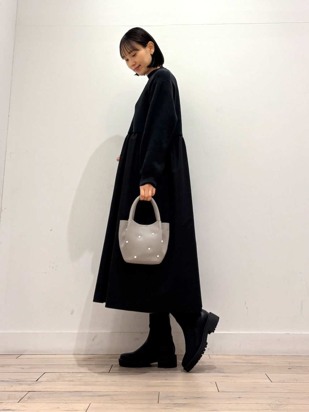 ブラック系のワンピース、グレー系のハンドバッグ、ブラック系のブーツを着用したレディースの秋コーディネートの4枚目の写真