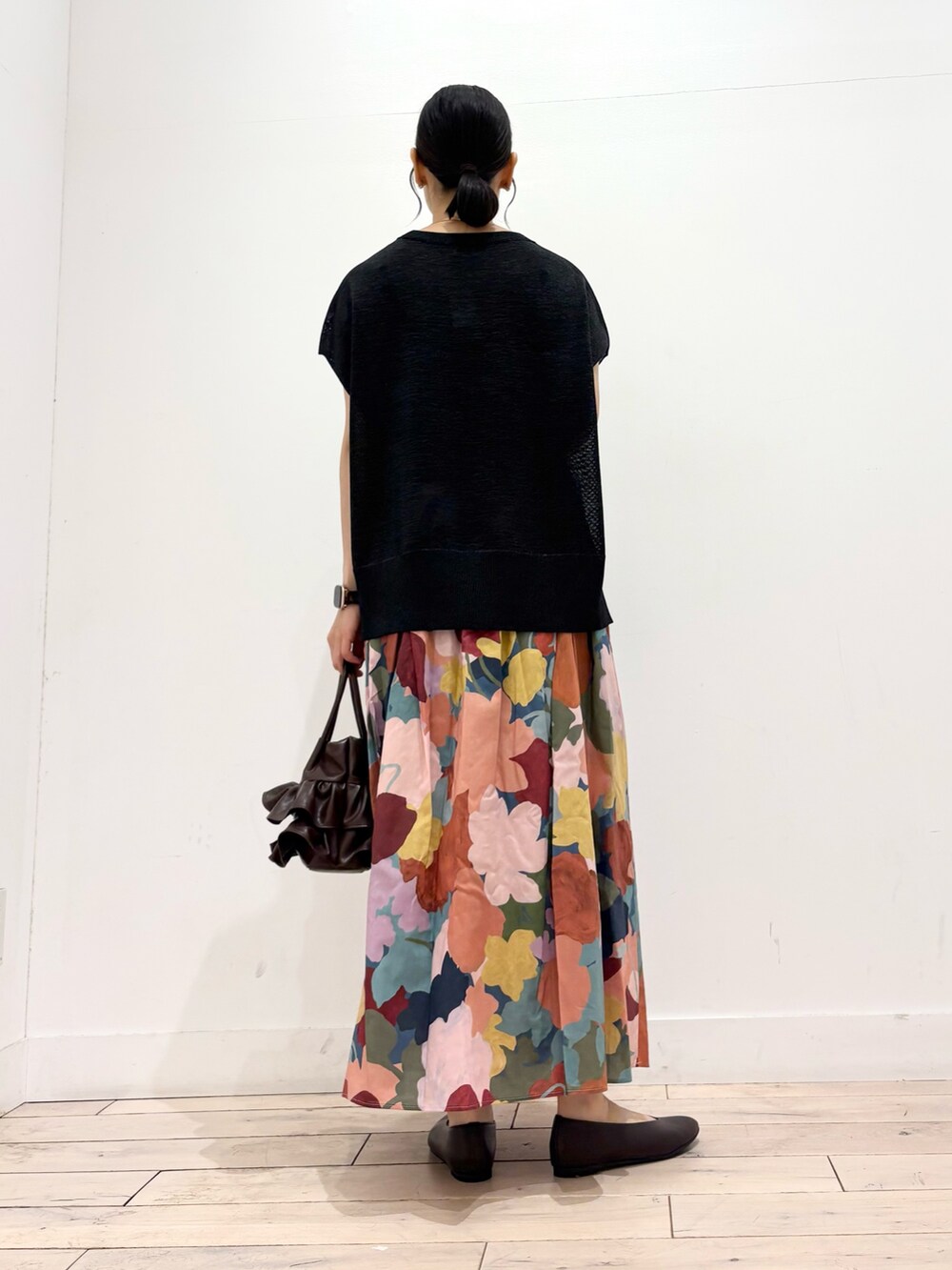 ブラック系のニット/セーター、ピンク系のスカート、ブラウン系のハンドバッグを着用したレディースの夏コーディネートの3枚目の写真