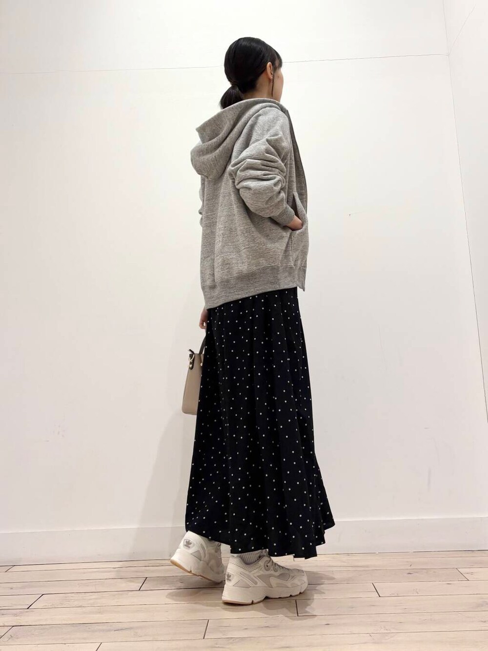 ベージュ系のトートバッグ、ブラック系のワンピース、グレー系のパーカーを着用したレディースの春コーディネートの2枚目の写真