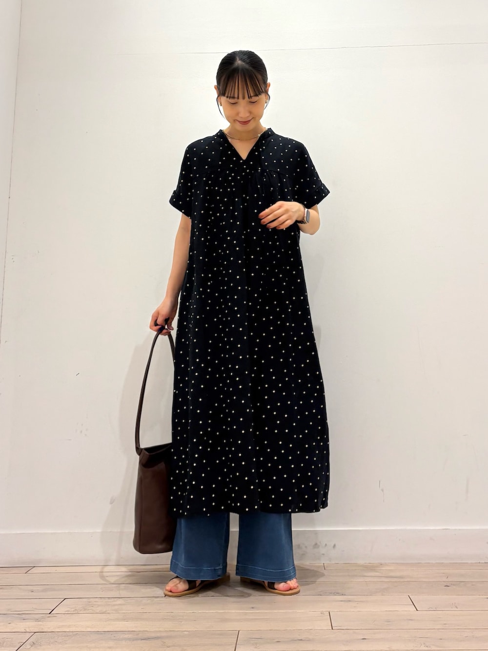 ブルー系のデニムパンツ、ブラウン系のサンダル、ブラック系のワンピースを着用したレディースの夏コーディネートの2枚目の写真