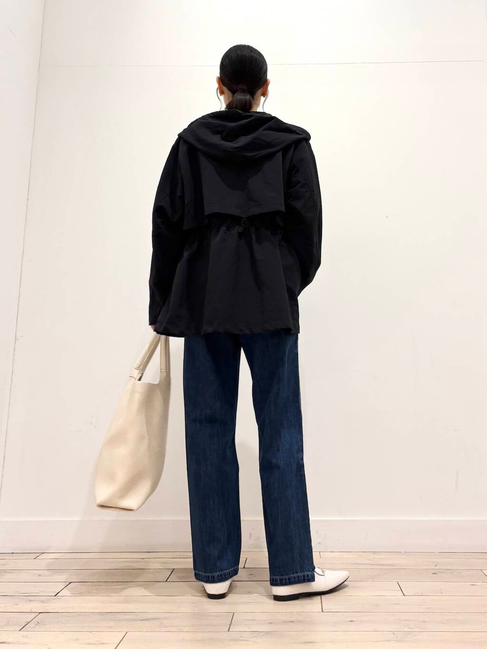 ブルー系のデニムパンツ、ブラック系のマウンテンパーカー、ホワイト系のローファーを着用したレディースの春コーディネートの4枚目の写真