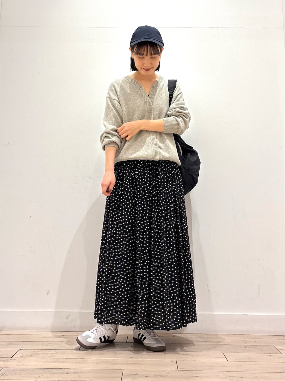 グレー系のニット/セーター、ブラック系のスカート、ブラック系のバックパック/リュックを着用したレディースの冬コーディネートの2枚目の写真