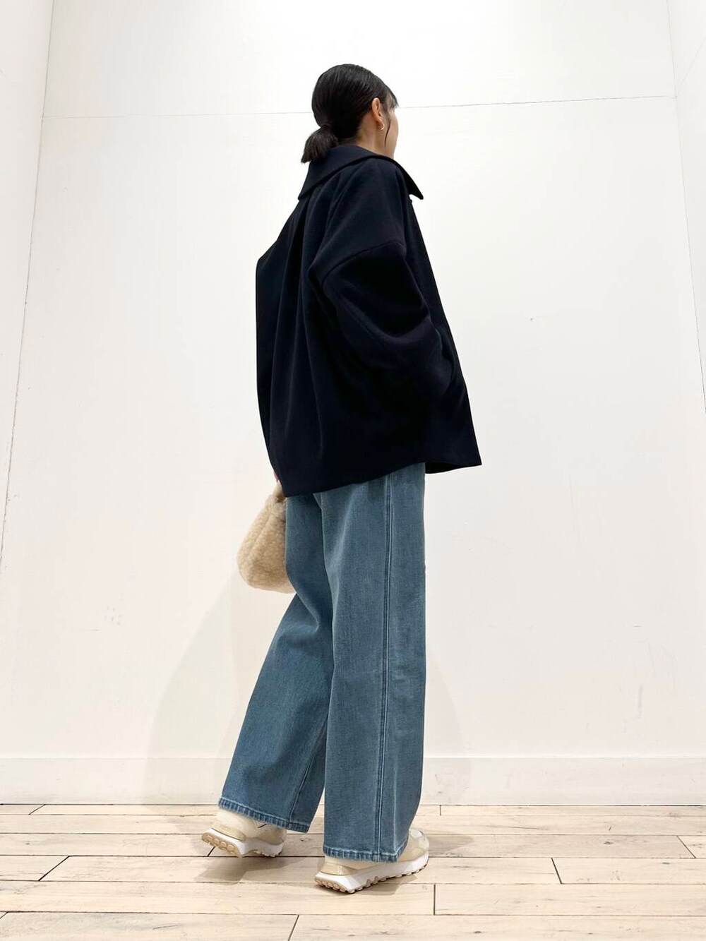 ホワイト系のスニーカー、ブルー系のその他アウター、ベージュ系のハンドバッグを着用したレディースの冬コーディネートの3枚目の写真