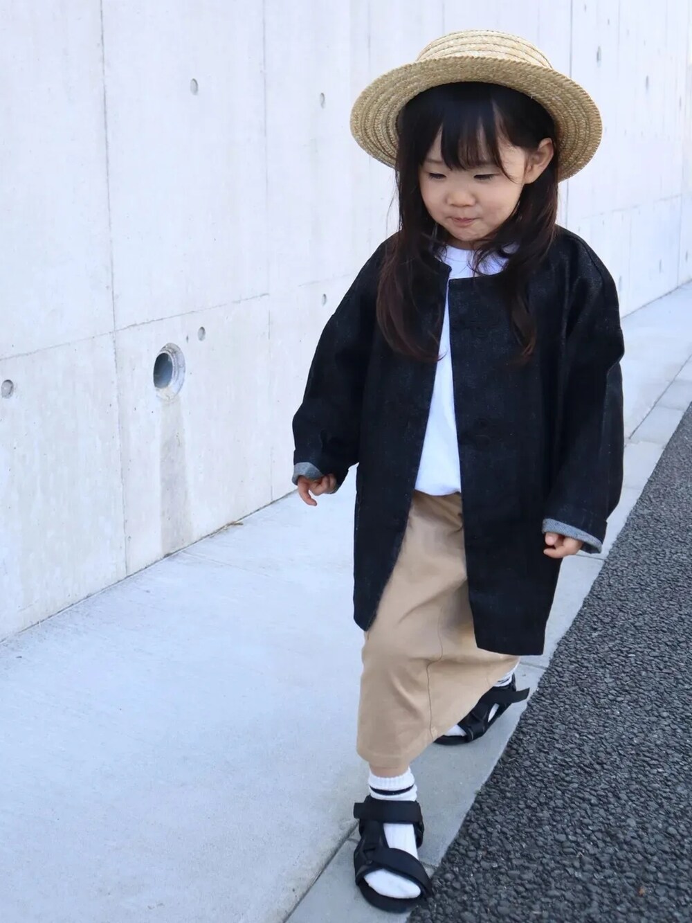 ブラック系のデニムジャケット、ベージュ系のスカート、ブラック系のサンダルを着用したキッズの春コーディネートの4枚目の写真