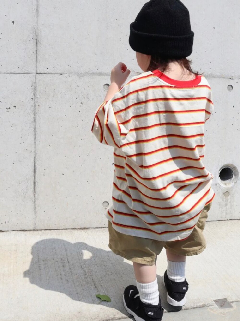 レッド系のTシャツ/カットソー、ベージュ系のパンツ、ブラック系のサンダルを着用したキッズの秋コーディネートの3枚目の写真