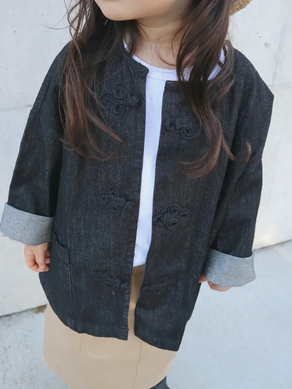 ブラック系のデニムジャケット、ベージュ系のスカート、ブラック系のサンダルを着用したキッズの春コーディネートの2枚目の写真