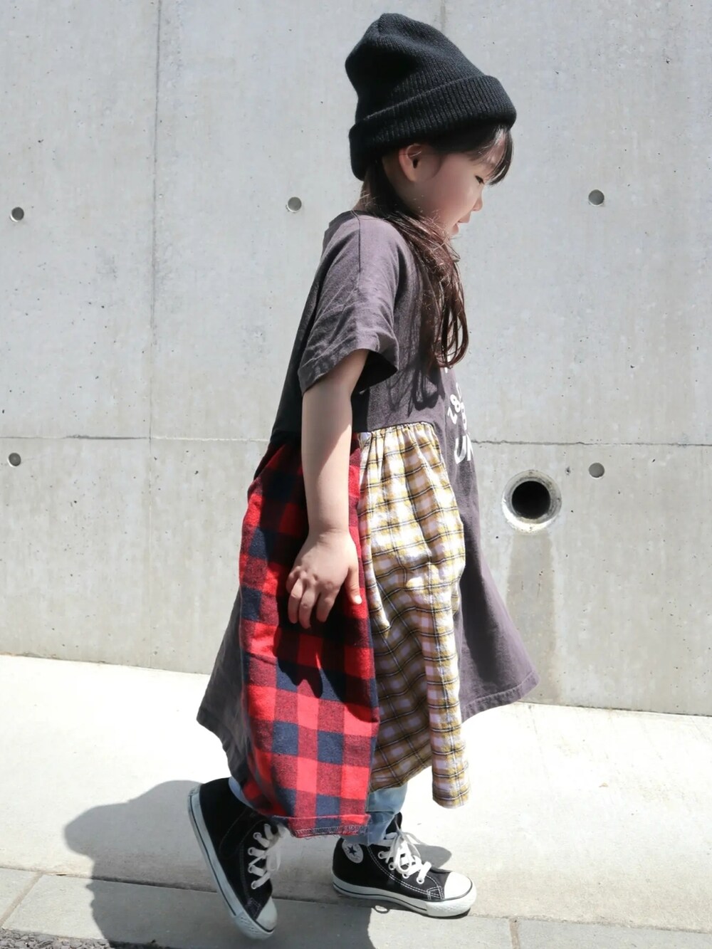 ブラック系のワンピース/ドレス、ブラック系のスニーカー、ブルー系のデニムパンツを着用したキッズの春コーディネートの2枚目の写真