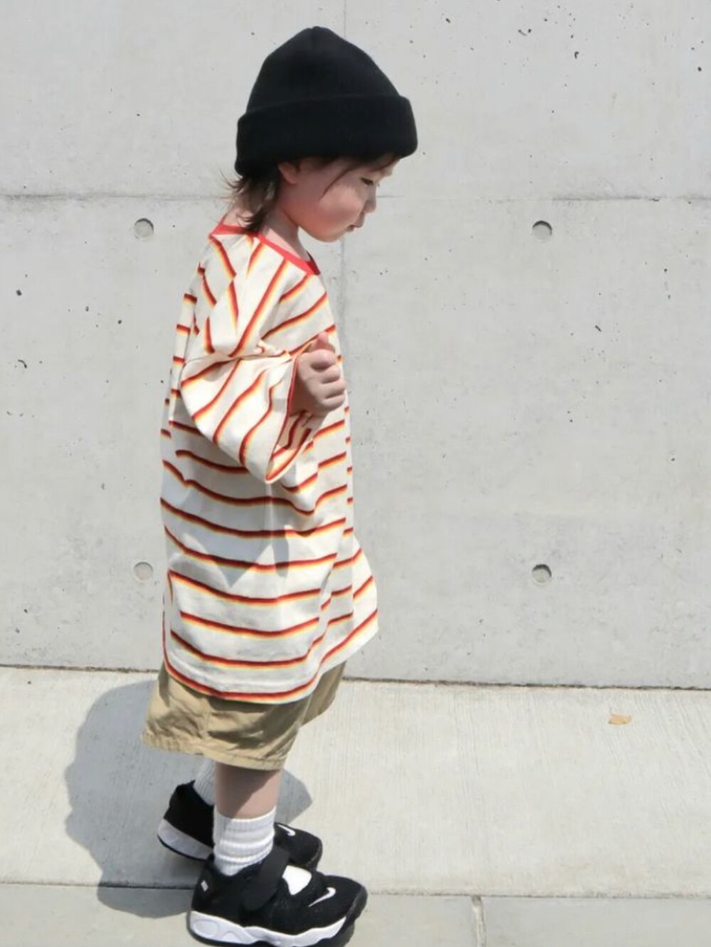 レッド系のTシャツ/カットソー、ベージュ系のパンツ、ブラック系のサンダルを着用したキッズの秋コーディネートの2枚目の写真