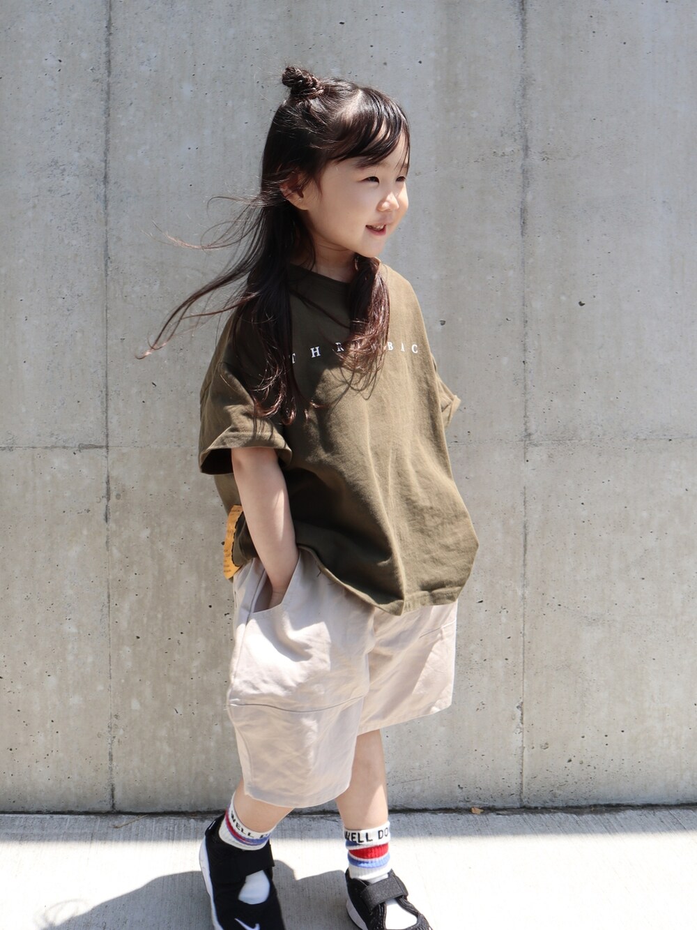 グリーン系のTシャツ/カットソー、ベージュ系のパンツ、ブラック系のサンダルを着用したキッズの春コーディネートの3枚目の写真