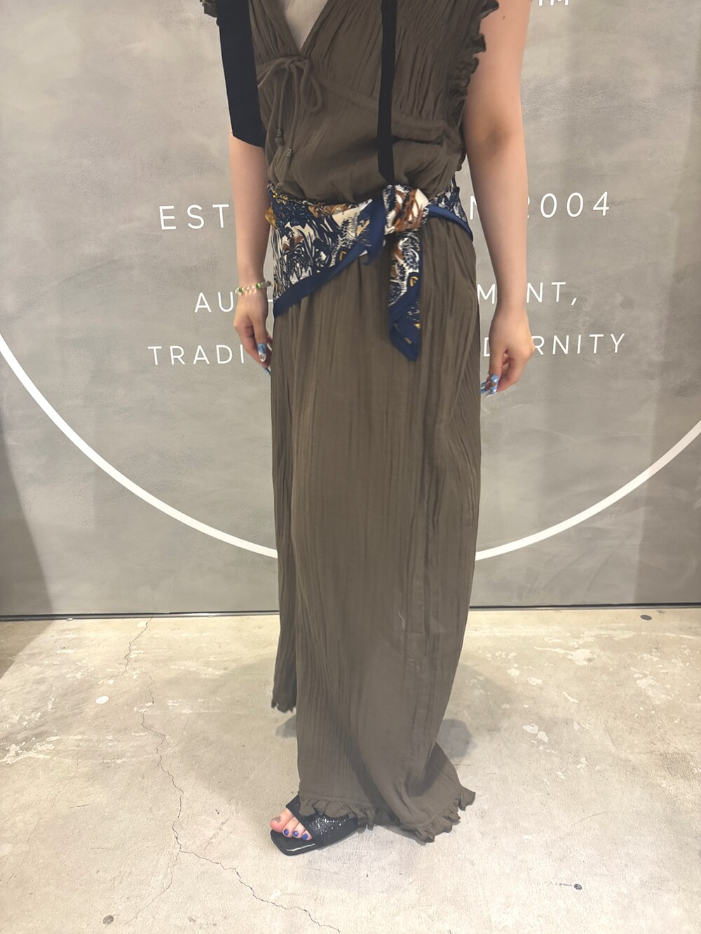 グリーン系のサロペット/オーバーオール、グレー系のタンクトップ、ブラック系のサンダルを着用したレディースの夏コーディネートの2枚目の写真