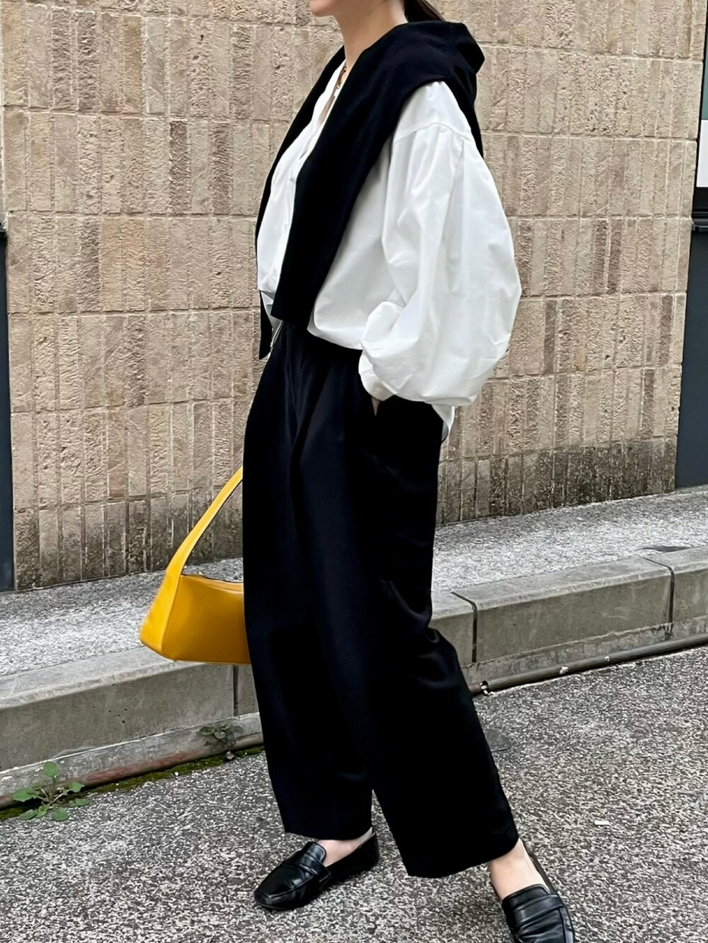 イエロー系のショルダーバッグ、ブラック系のスラックス、ブラック系のローファーを着用したレディースの春コーディネートの2枚目の写真