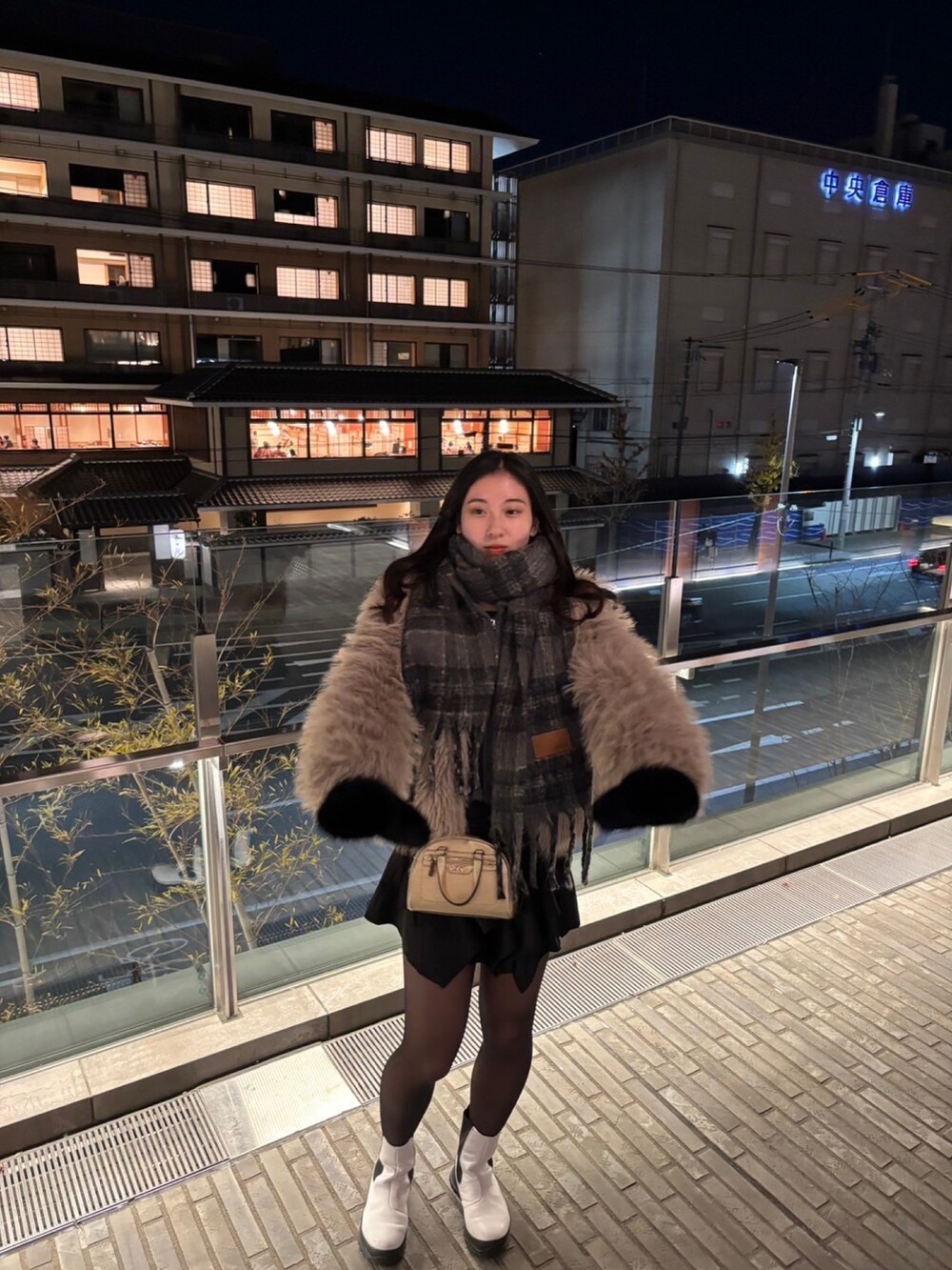 ブラック系のスカート、ベージュ系のノーカラーコート、グレー系のマフラーを着用したレディースの春コーディネートの2枚目の写真